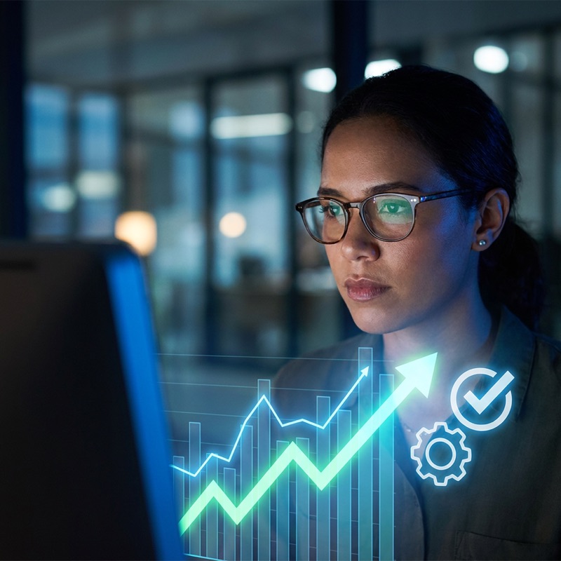 A business analyst looks at a glowing forecast chart on her screen with an upward trend line connected to automated action icons including a gear and a checkmark